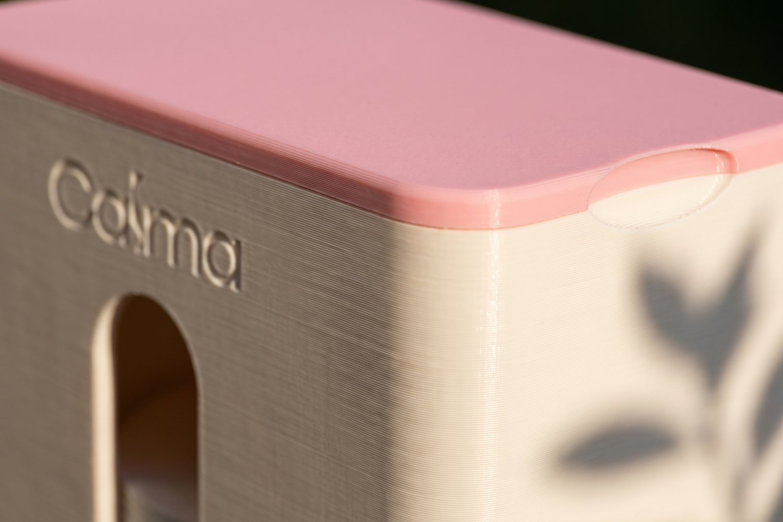 Close-up van het roze deksel en het CALMA logo, met zichtbare 3D-printlagen in strijklicht